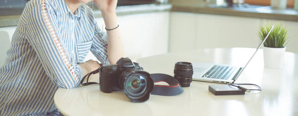Женщина-фотограф сидит на столе с ноутбуком