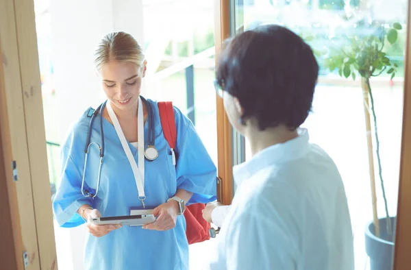 Femme médecin avec presse-papiers lors de la visite à domicile tout en entrant dans la maison — Photo