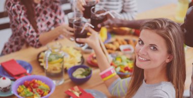 Ahşap masada otururken birlikte yemek yiyen bir grup insanın üst düzey görüntüsü. Masada yemek var. İnsanlar fast food yiyor..