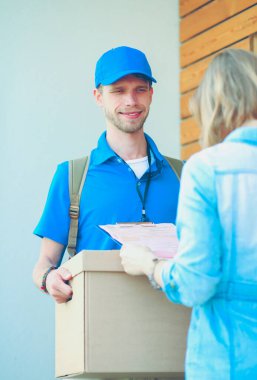 Mavi üniformalı gülümseyen kurye servis konseptine paket kutusu teslim eden teslimatçı. Mavi üniformalı gülümseyen teslimatçı.
