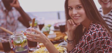 Ahşap masada otururken birlikte yemek yiyen bir grup insanın üst düzey görüntüsü. Masada yemek var. İnsanlar fast food yiyor..