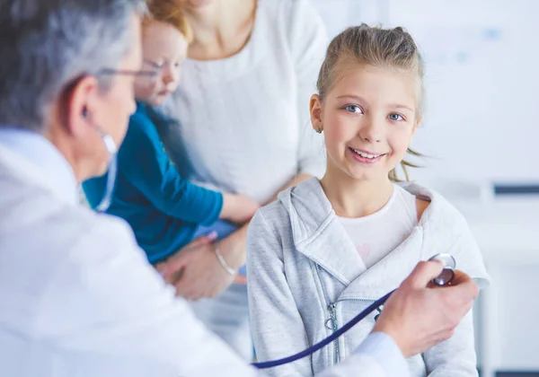 Dziewczyna i lekarz ze stetoskopem słuchający bicia serca — Zdjęcie stockowe
