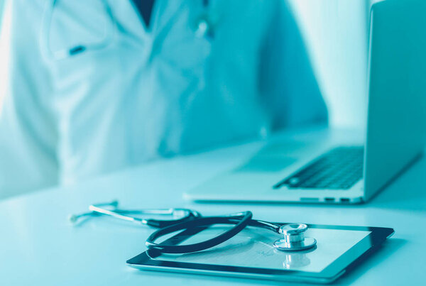 Медицинское оборудование: синий стетоскоп и таблетка на белом фоне. Медицинское оборудование