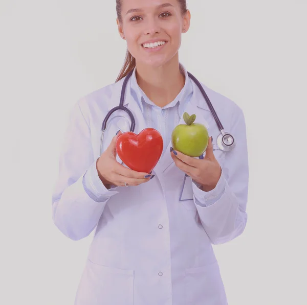 Mooie glimlachende vrouwelijke arts met rood hart en groene appel. Vrouwelijke dokter — Stockfoto