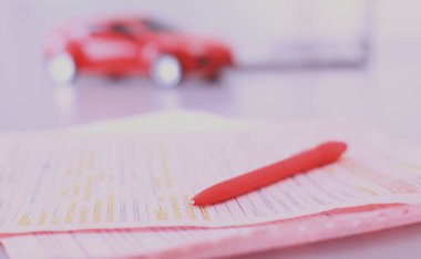 Bilgisayarın yanında kalem ve kırmızı bir oyuncak araba olan bir dizüstü bilgisayar. Nesne çekimi