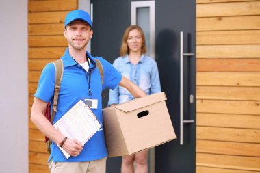 Mavi üniformalı gülümseyen kurye servis konseptine paket kutusu teslim eden teslimatçı. Mavi üniformalı gülümseyen teslimatçı.