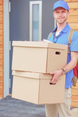 Mavi üniformalı gülümseyen kurye servis konseptine paket kutusu teslim eden teslimatçı. Mavi üniformalı gülümseyen teslimatçı.