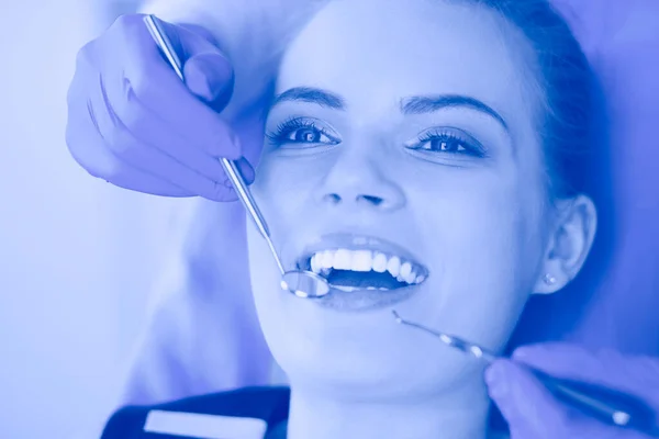 Mujer joven con la boca abierta examinando la inspección dental en el consultorio del dentista. — Foto de Stock