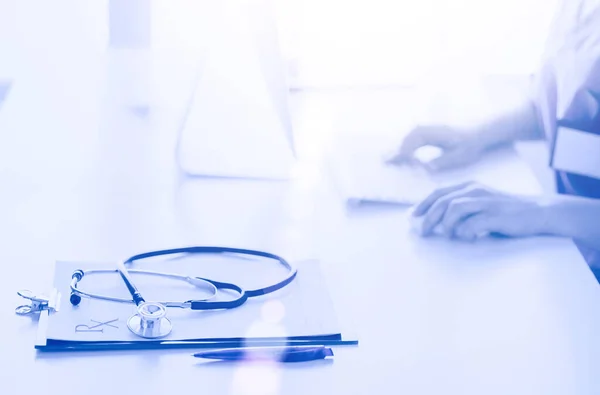 Portrait of female physician using laptop computer while standing near reception desk at clinic or emergency hospital