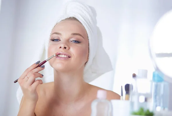Uma foto de uma jovem mulher aplicando pó facial no banheiro — Fotografia de Stock