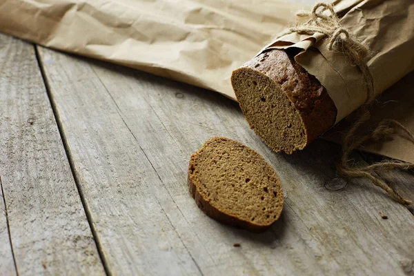 Brotscheiben in Papier verpackt auf Holztisch — Stockfoto