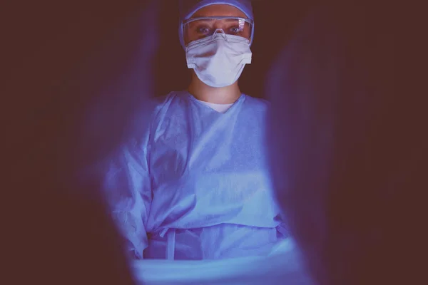Equipo de médicos en cirugía en un fondo oscuro. —  Fotos de Stock