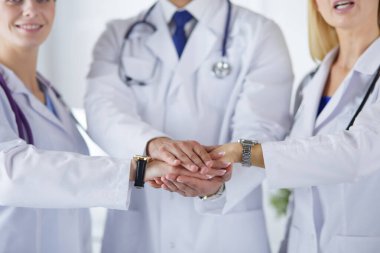 Doktorlar ve hemşireler tıbbi bir ekipte el ele tutuşuyorlar.