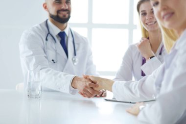 Doktor ofiste erkek bir hastayla el sıkışıyor.