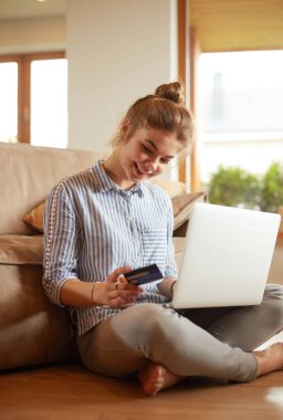 Online alışveriş için kredi kartı ve dizüstü bilgisayar kullanan güzel genç kadın