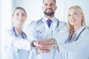 Doktorlar ve hemşireler tıbbi bir ekipte el ele tutuşuyorlar.