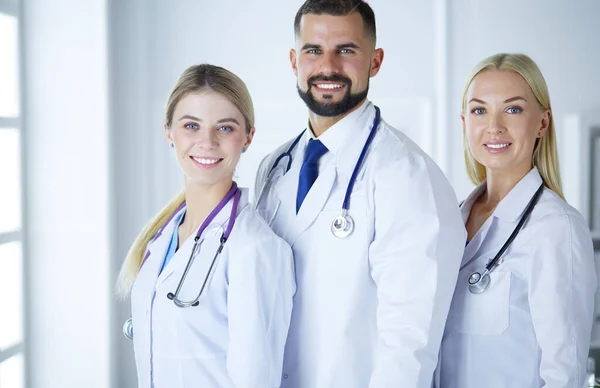 Médicos sonrientes todos de pie juntos en una sala de consultoría —  Fotos de Stock