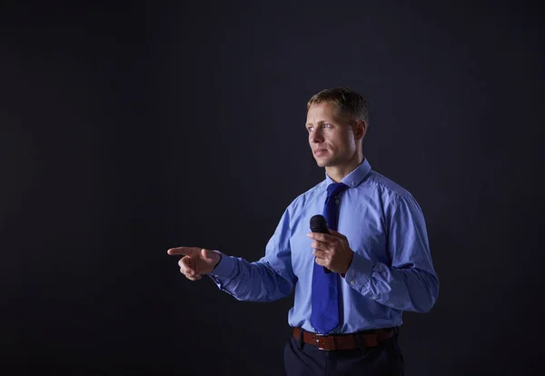 Een man met een microfoon terwijl hij met zijn vinger naar je wijst. — Stockfoto