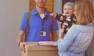 Mavi üniformalı gülümseyen kurye servis konseptine paket kutusu teslim eden teslimatçı. Mavi üniformalı gülümseyen teslimatçı.