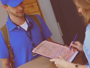 Mavi üniformalı gülümseyen kurye servis konseptine paket kutusu teslim eden teslimatçı. Mavi üniformalı gülümseyen teslimatçı.
