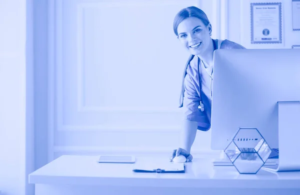 Πορτραίτο γυναίκας γιατρού που χρησιμοποιεί φορητό υπολογιστή ενώ στέκεται κοντά στο γραφείο υποδοχής σε κλινική ή νοσοκομείο έκτακτης ανάγκης — Φωτογραφία Αρχείου