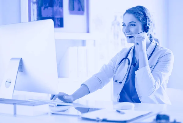 Young practitioner doctor working at the clinic reception desk, she is answering phone calls and scheduling appointments — Stock Photo, Image