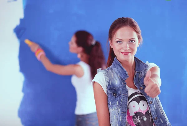 Dos hermosas mujeres jóvenes pintando paredes, sentadas. Dos Hermosa joven mujer . — Foto de Stock