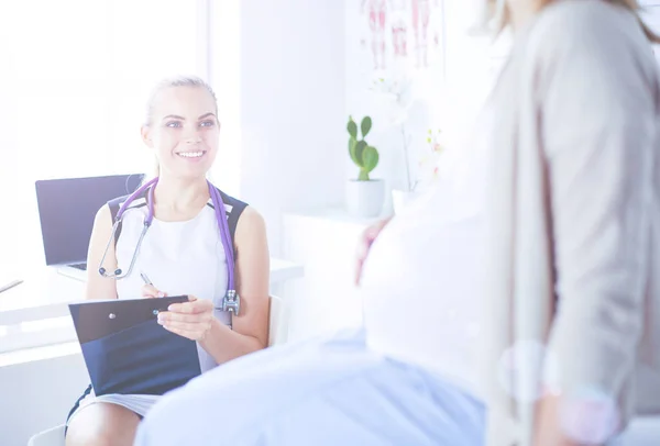 Giovane donna medico con stetoscopio e tablet che parla con una donna incinta in ospedale. — Foto Stock