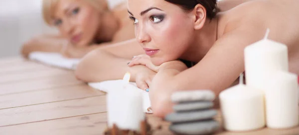 Duas belas amigas deitadas em mesas de madeira com a cabeça em toalhas esperando por sua massagem no spa — Fotografia de Stock