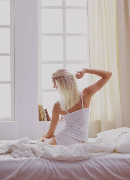 Γυναίκα που τεντώνεται στο κρεβάτι μετά το ξύπνημα, πίσω όψη — Φωτογραφία Αρχείου