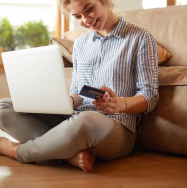 Online alışveriş için kredi kartı ve dizüstü bilgisayar kullanan güzel genç kadın