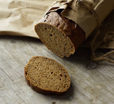 Dilimlenmiş ekmek somunu tahtadan masanın üzerinde kağıda sarılmış.