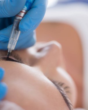 Kaşlar için kalıcı makyaj. Güzellik salonunda kalın kaşlı güzel bir kadın..