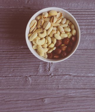 Ahşap masa üzerinde organik karışık kuruyemiş ile kase