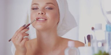 Genç bir kadının banyoya yüz pudrası sürerken fotoğrafı.