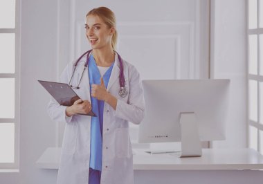 Kadın doktor hastanede dosyayla bekliyor.