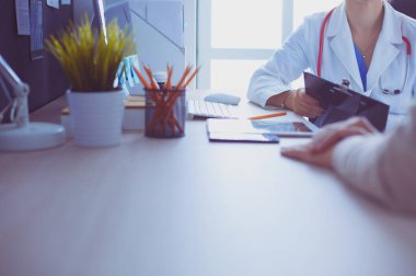 Bir doktor konuşuyor ve bir hastayı muayene ediyor.