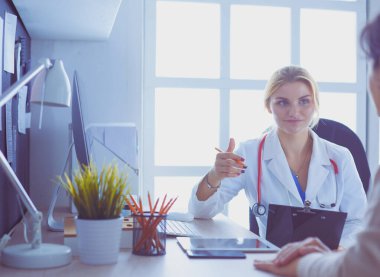 Kadın doktor hastaya danışmanlık yaparken başvuru formu tutuyor