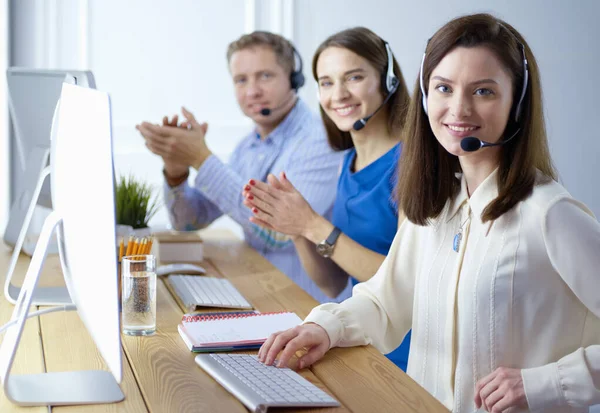 Porträt eines jungen Callcenter-Betreibers mit Headset und Kollegen, die im Hintergrund im Büro arbeiten — Stockfoto