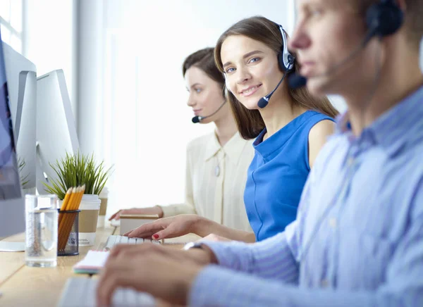 Lachende call center medewerkers zitten in de rij met hun headset — Stockfoto