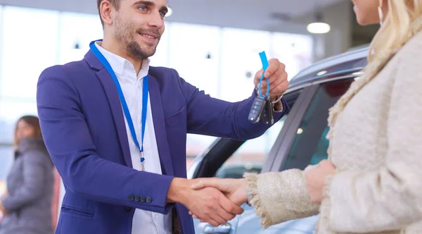 車の販売員は車の販売代理店で幸せな顧客に車を販売し、キーの上に手. — ストック写真