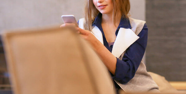 Young woman sitting on comfortable sofa with cup on coffee in hands in white room