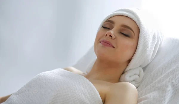 Jovem deitada em uma mesa de massagem, relaxando com os olhos fechados. Mulher. Salão de Spa — Fotografia de Stock