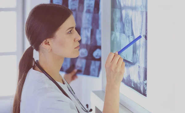 Giovane medico femminile sorridente con stetoscopio che punta ai raggi X presso lo studio medico — Foto Stock