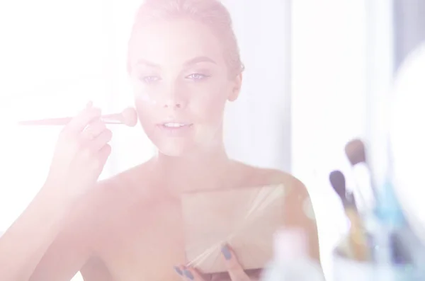 Uma foto de uma jovem mulher aplicando pó facial no banheiro — Fotografia de Stock