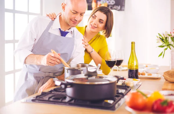 Couple attrayant dans la cuisine amoureuse et ouvre le vin dans la cuisine pendant qu'ils préparent le dîner pour une soirée romantique — Photo