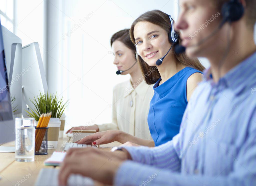 Smiling call center employees sitting in line with their headset