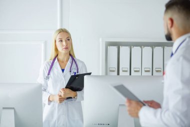 Kadın doktor hastanede dosyayla bekliyor.