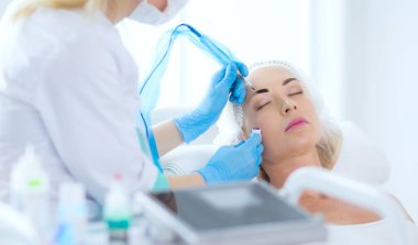 Kaşlar için kalıcı makyaj. Güzellik salonunda kalın kaşlı güzel bir kadın..