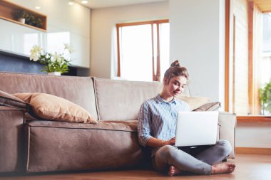 oturma odasında yere üstünde laptop ile mutlu bir kadın
